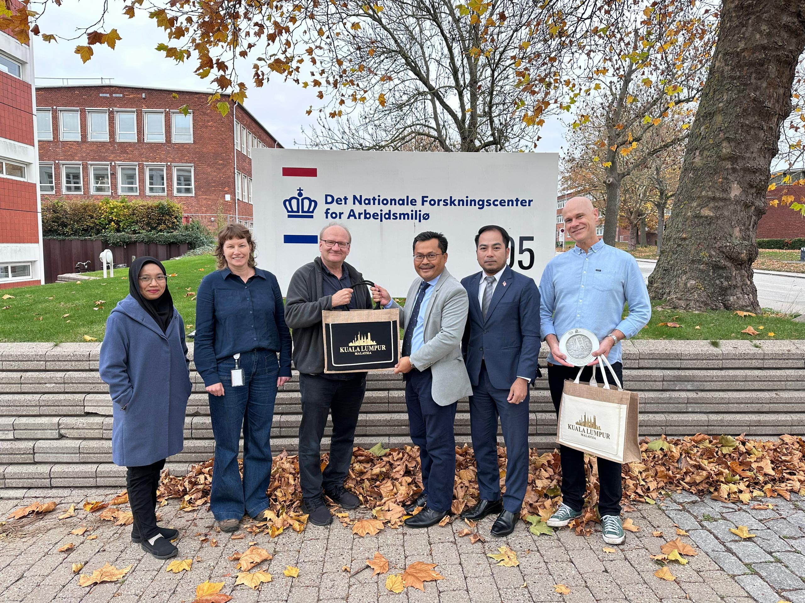 Ayop salleh menyerahkan cenderahati niosh kepada professor keld alstrup jensen baju biru yang mewakili national research center for the working environment nfa denmark